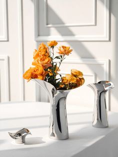 two silver vases with yellow flowers in them