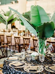 the table is set with place settings and flowers in vases on top of it