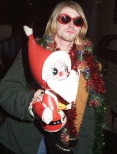 a man wearing sunglasses and holding an inflatable santa clause doll with his arm wrapped around him