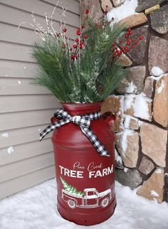 a red mason jar filled with greenery sitting on top of snow covered ground