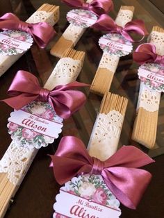 some wooden sticks with pink bows and name tags on them are sitting on a table