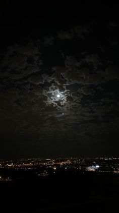 the full moon is shining brightly in the night sky over a cityscape with clouds