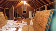 an attic with wood flooring and exposed rafters on the ceiling, while a man stands in the doorway