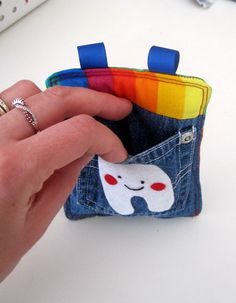 a hand holding a small pocket with a toothbrush in it and a rainbow ring