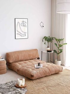 a living room with a futon couch and rugs on the floor in front of a window