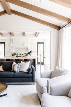 a living room with two couches and a table in front of the window that is open