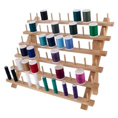 a wooden rack with many different spools of thread on top of each shelf