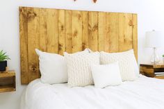 a bed with white pillows and two wooden headboards on each side of the bed