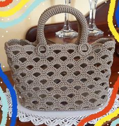 a crocheted purse sitting on top of a table next to two wine glasses