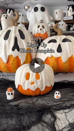 halloween pumpkins decorated with white and black icing, sitting on a table in front of fake ghost heads