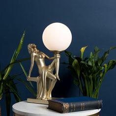 a lamp that is sitting on top of a table next to a book and potted plant