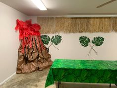 a green table with red ribbons on it in front of two palm leaf wall hangings