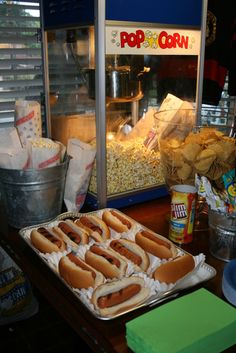 hotdogs and corn on a tray in front of a popcorn machine at a restaurant