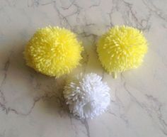 three yellow and white pom - poms sitting on a marble countertop next to each other