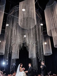 a bride and groom standing under chandelier at the end of their wedding ceremony