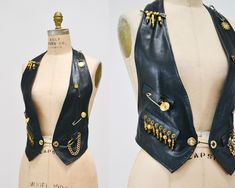 This Rock star vest Features: * Soft Black leather in a chic style * Gold trim and chain details * Open back  * adjustable back tab * Front pin closure * Fully lined  Brand Dangerous Minds  Size Small  100% Leather Beautiful Vest! Great vintage condition with some minor signs of wear in the leather,  Waist adjusts to 30-34" widest https://www.etsy.com/shop/Hookedonhoney ** Tik Tok | hookedonhoneyvintage ** Instagram | hookedonhoneyvintage Star Vest, Fitted Vintage Leather Vest, Vintage Leather Vest Outerwear, Leather Sleeveless Vest With Button Closure, Black Leather Vest Vintage, Sleeveless Leather Vest With Button Closure, Black Leather Vest, Biker Vest, Dangerous Minds