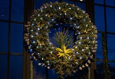 a christmas wreath is lit up in front of a window