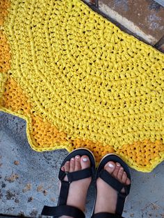 a pair of feet standing on top of a yellow and black rug next to a sidewalk