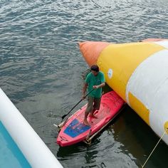 a man standing on a paddle board next to an inflatable buoy boat