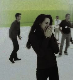 a woman standing in the snow with her hands to her face and other people behind her