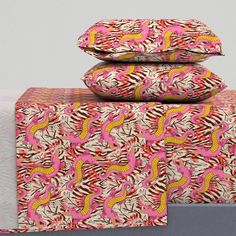 three pillows stacked on top of each other in front of a white wall with pink and yellow designs