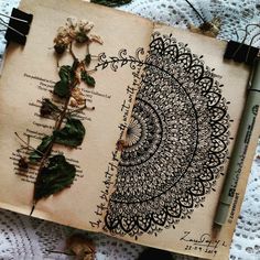 an open book with drawings on it sitting on top of a table next to flowers