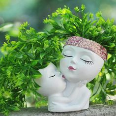 a white ceramic figurine with eyes closed and head resting on another one's back