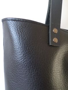 Large everyday casual vegan leather tote bag in black with real leather handles. * Exterior: - High quality vegan/faux leather in black color. * Interior: - Charcoal gray Italian natural cotton. * Two inside slip pockets for personal belongings like phone, keys, etc. * Real leather handles in black attached with antique toned brass rivets * Closes with magnetic snap closure reinforced with natural leather * Additionally lined for better structure. Measurements: Height: 15 inches Width of the bag Minimalist Leather Bucket Bag With Double Handle, Everyday Bucket Bag With Double Leather Handles, Workwear Bucket Bag With Leather Lining, Black Shoulder Bag With Leather Lining And Double Handle, Textured Leather Tote Bucket Bag For Everyday Use, Textured Leather Bucket Bag Tote For Everyday Use, Everyday Textured Leather Tote Bucket Bag, Everyday Textured Leather Rectangular Bucket Bag, Black Leather Lined Tote Bag