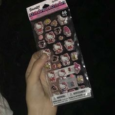 a person holding up a package of hello kitty magnets in their left hand,