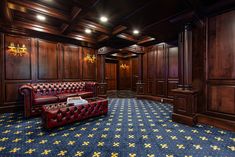 a large room with wooden paneling and red leather couches in front of a blue carpeted floor