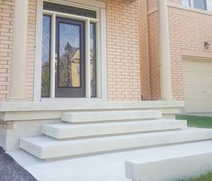 a front door with steps leading up to it and a brick building in the background