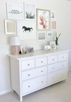 a white dresser with many pictures on the wall