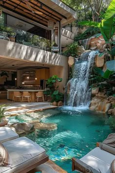 an outdoor pool with waterfall and lounge chairs in the foreground, surrounded by greenery