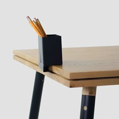 a wooden table with two pencils and a box on it's end,