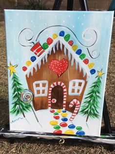 a painting of a gingerbread house decorated with candy canes and candies on a easel