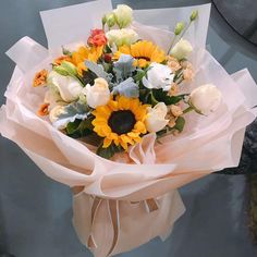 a bouquet of sunflowers and tulips wrapped in paper