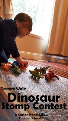 a young boy playing with toy dinosaurs on the floor in front of a large window