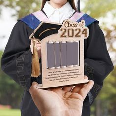 a person holding up a wooden graduation plaque