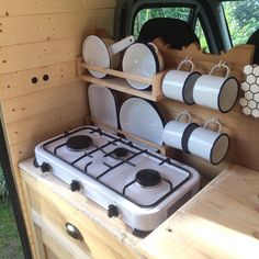 a stove top oven sitting in the back of a truck with plates and cups on it