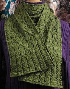 a woman wearing a green knitted scarf and purple sweater with flowers in the background