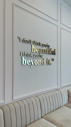 there is a white couch in front of a wall with some words on the wall