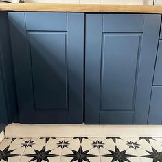 a kitchen with blue cabinets and black stars on the floor, in front of a counter top