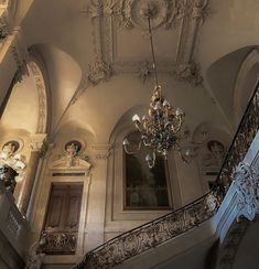 the chandelier is hanging from the ceiling above the stairs in an old building