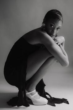 a black and white photo of a woman sitting on the ground with her legs crossed