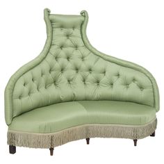 an upholstered green couch with fringe trim