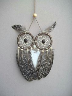 an owl is hanging from the wall with feathers and beads on it's head