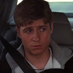 a young man sitting in the back seat of a car with his head turned to the side