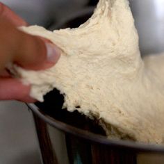 a person is kneading some dough into a metal bowl and mixing it together