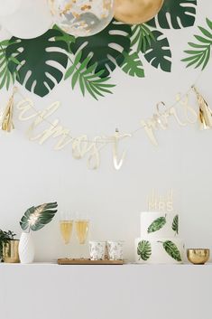 a table topped with cake and drinks on top of a white mantle covered in greenery