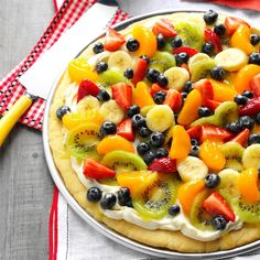 a pizza with fruit on it sitting on top of a table